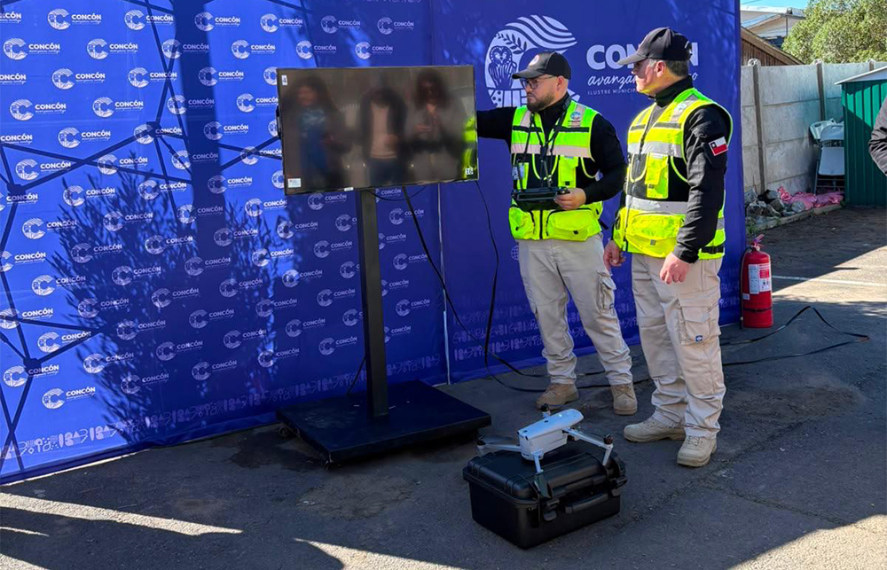 Funcionarios de Seguridad Pública Municipal de Concón realizan una demostración en vivo del nuevo dron de vigilancia frente a una pantalla