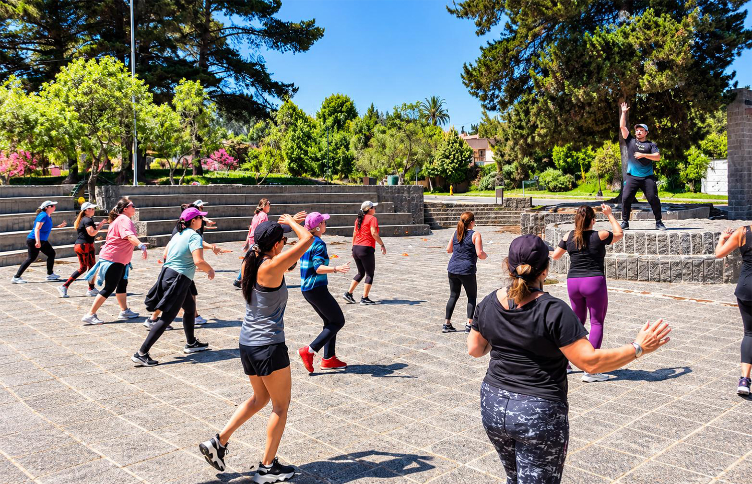 Vecinas siguen la coreografía de la clase de baile entretenido sobre el pavimento de la plaza