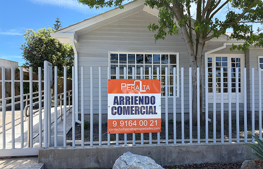 Casa de madera gris con reja blanca y un letrero naranja que dice Arriendo Comercial, en avenida Blanca Estela